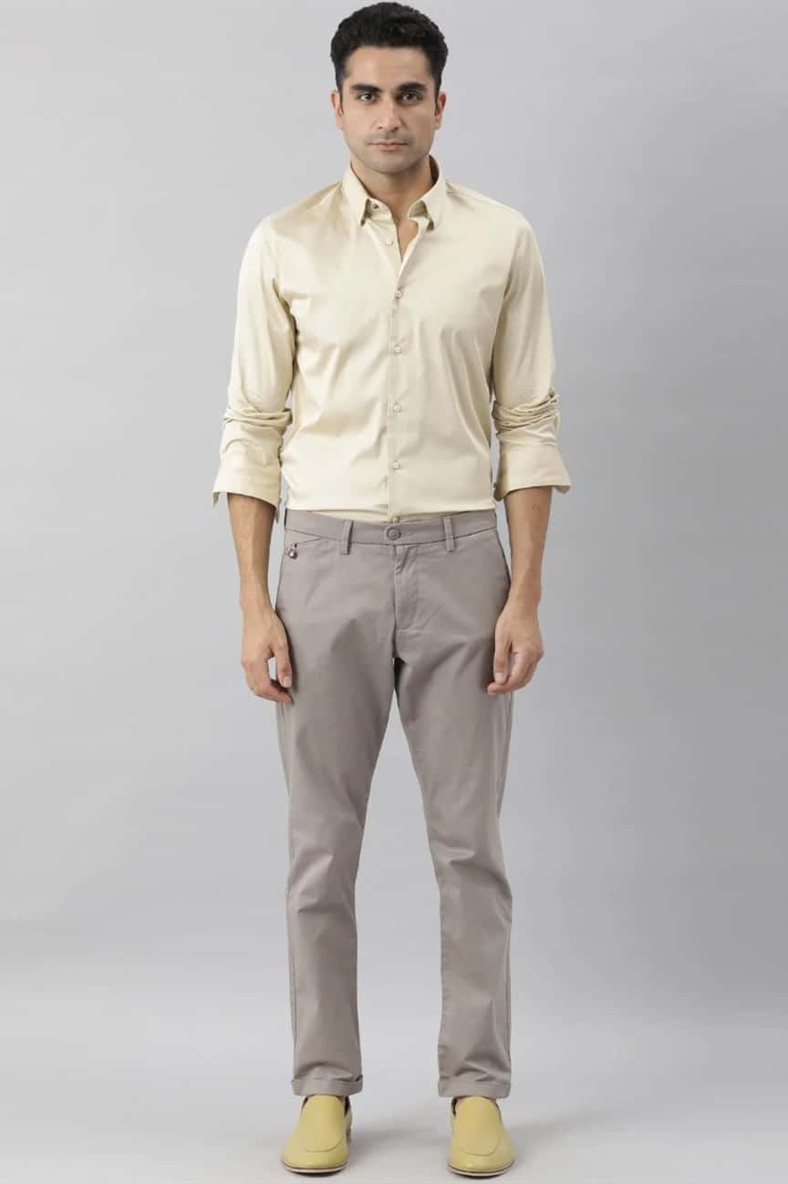 a young man wearing a gray shirt and khaki pants Stock Photo by Icons8